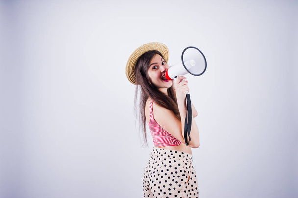 Portrait of a gorgeous young girl in swimming suit and hat talks into megaphone in studio. - Foto, Imagen