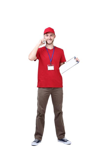 Delivery man with clipboard talking on smartphone isolated on white background - Foto, afbeelding