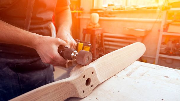 Lähikuva nuoren miehen rakentaja puuseppä on yhtä kuin kiillottaa puulevy kiillotus kone tai satunnainen kiertoradalla hiomakone työpajassa
 - Valokuva, kuva