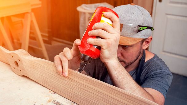Close-up de um jovem construtor carpinteiro é igual a cola placa de madeira na oficina
 - Foto, Imagem
