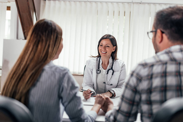 Front image of female doctor having a consultation with a couple. - Photo, Image