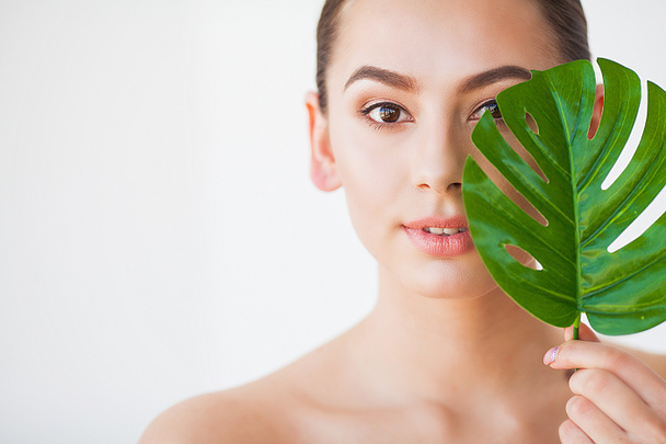 Skincare. Beautiful Woman Portrait on White Background With Clean Skin and Green Leaf in Hand. - Fotografie, Obrázek
