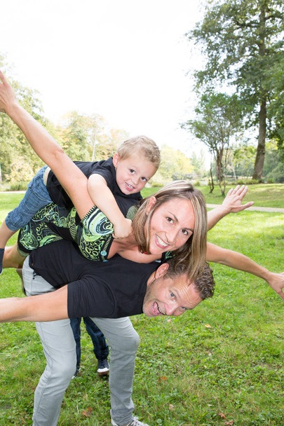 family piggyback with beautiful mother handsome blond father and boy child cheerful - Photo, image
