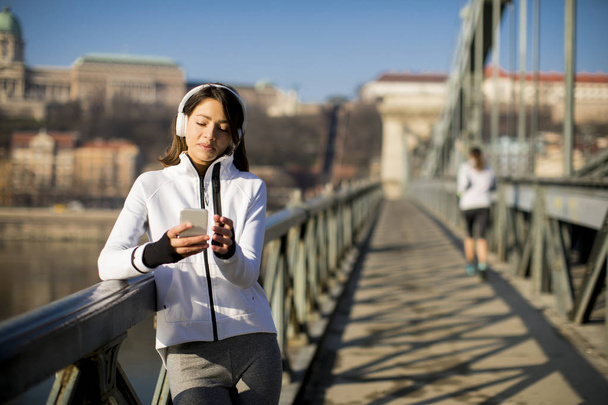 Mladý sportovec žena s mobilním telefonem na bridhe v Budapešti, Maďarsko - Fotografie, Obrázek