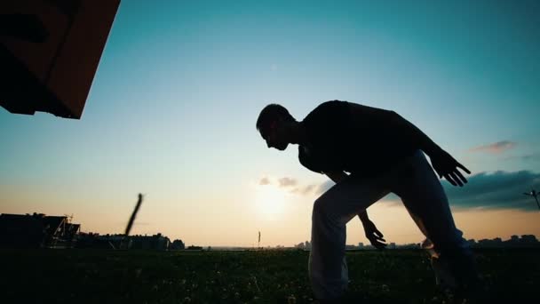 Homem treina capoeira na grama, ao pôr do sol, em câmera lenta
 - Filmagem, Vídeo