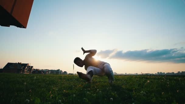 Athlétisme masculin entraîne capoeira sur l'herbe contre le soleil le soir d'été
 - Séquence, vidéo