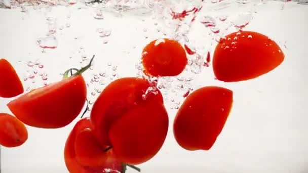 Tomaten groenten vallen in water met spatten en bubbels, Slowmotion close-up - Video