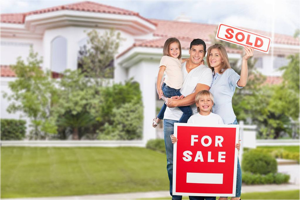 Familia feliz de cuatro con en venta signo por casa
 - Foto, Imagen