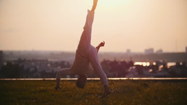 Homme fort démontre physiquement des trucs très cool sur l'herbe sur le fond d'un coucher de soleil rose
 - Séquence, vidéo