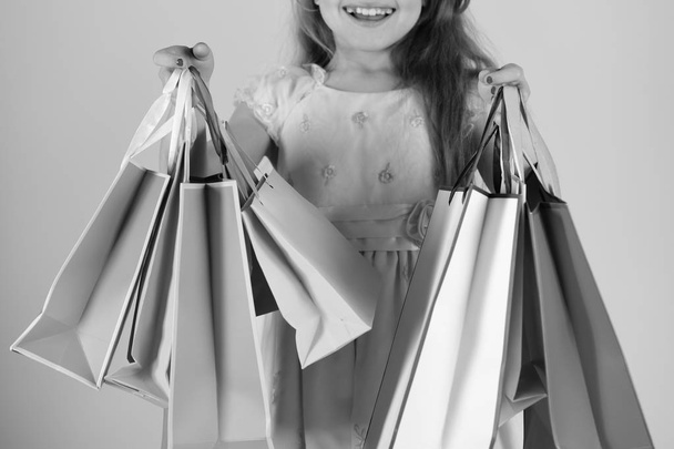 Shopaholic and childhood concept. Lady shopper in dress, wavy hair. Girl holds shopping bags - Fotó, kép