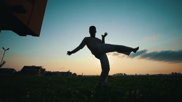 Силуэт мужчины, танцующего капоэйру на закате, летним вечером
 - Кадры, видео