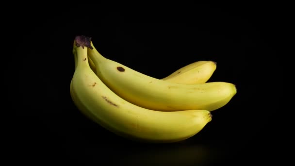 Un ramo de plátanos orgánicos amarillos girando lentamente sobre fondo negro
 - Metraje, vídeo