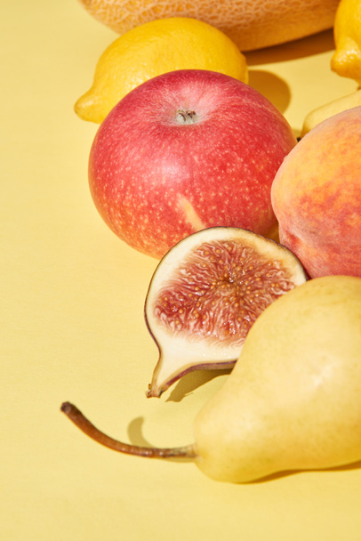 close-up view of fresh ripe pear, apple, peach, fig and lemons on yellow - Foto, Imagem