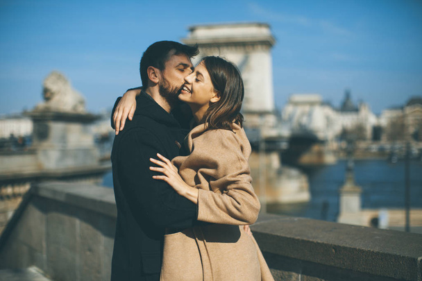 Joven feliz pareja atractiva en el amor abrazo con el fondo de la magnífica vista de Budapest, Hungría
 - Foto, Imagen