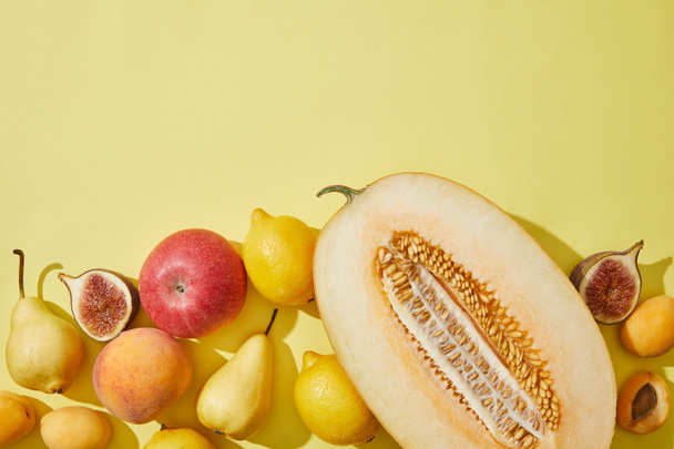 top view of halved melon and fresh ripe fruits on yellow background - Photo, Image