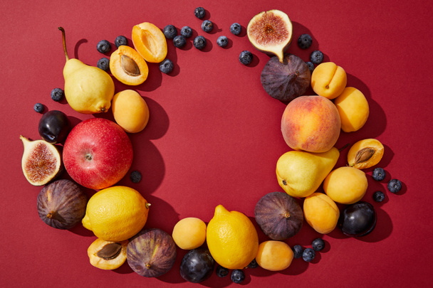 vista superior de várias frutas frescas maduras e doces de verão no fundo vermelho
  - Foto, Imagem