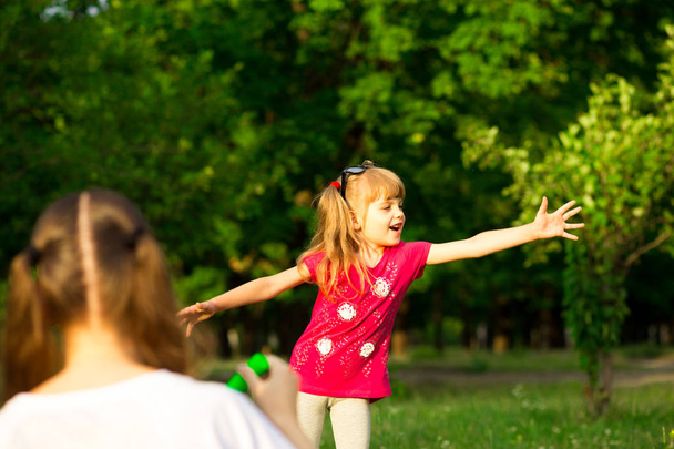 Jovem mãe e filha brincando no parque com bolhas de sabão. Amor família, paternidade, infância
 - Foto, Imagem