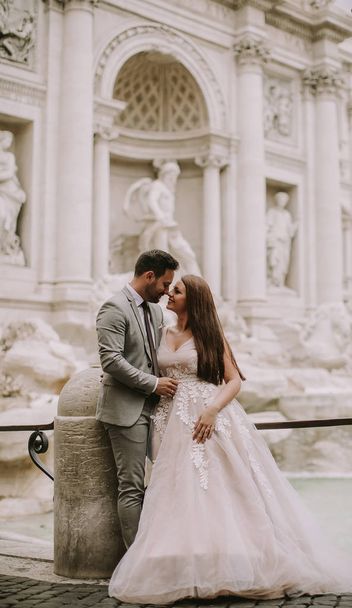 Net getrouwd bruid en bruidegom poseren voor Trevifontein (Fontana di Trevi), Rome, Italië - Foto, afbeelding