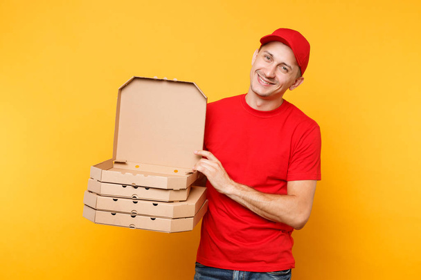 Liefermann mit roter Mütze, T-Shirt, das Pizzakartons bestellt, isoliert auf gelbem Hintergrund. männlicher Angestellter Pizzamann oder Kurier in Uniform mit italienischer Pizza in Pappschachtel. Dienstleistungskonzept - Foto, Bild