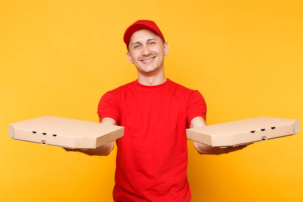 Repartidor en gorra roja, camiseta con cajas de pizza para pedidos de comida aisladas sobre fondo amarillo. Hombre empleado pizzaman o courier en uniforme sosteniendo pizza italiana en caja plana de cartón. Concepto de servicio
 - Foto, imagen