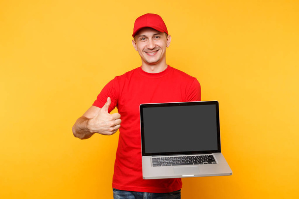 Kézbesítő, elszigetelt, a sárga-narancssárga háttérrel. Szakmai férfi alkalmazott futár a piros sapka, póló rendelkező laptop számítógép-val üres üres képernyő. Szolgáltatási koncepció. Másolja a hely. Mintadarab-template - Fotó, kép