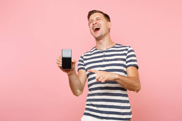 Retrato del hombre en camiseta a rayas que muestra la cámara del teléfono móvil con espacio de copia de pantalla vacía en blanco y negro aislado sobre un fondo rosa pastel de tendencia. Concepto de emociones sinceras. Área publicitaria
 - Foto, Imagen