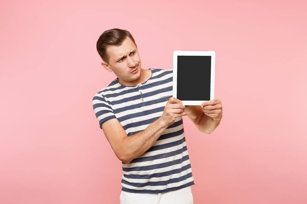 Портрет молодого чоловіка, який тримає планшетний комп'ютер з порожнім чорним порожнім екраном, відображає простір для копіювання, ізольований на тренді пастельно-рожевого фону. Технологія концепції способу життя. Рекламна зона
 - Фото, зображення