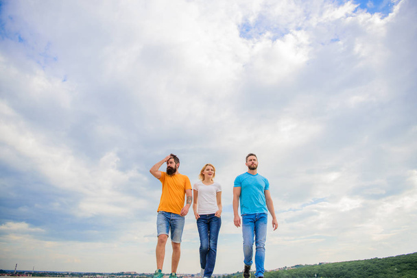 United group purposefully moves forward. Men and woman walks dramatic cloudy sky background. True friendship grow with destiny obstacles. United threesome true friends. Keep moving trough long way - Foto, afbeelding