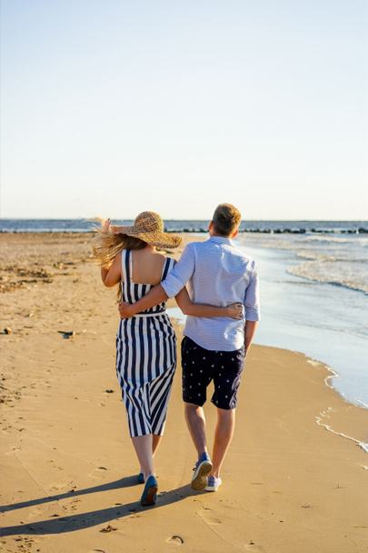 rear view of affectionate couple walking on sandy beach on summer day - Photo, Image
