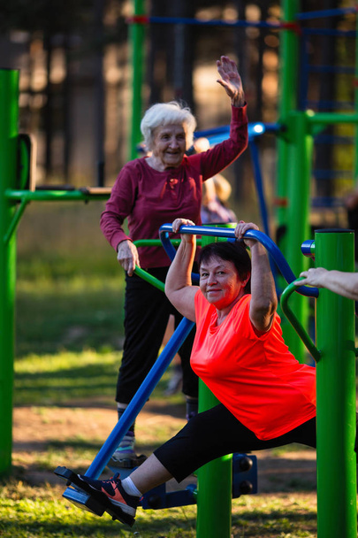 Elderly women  doing exercises on the sport playground in the park. - Photo, Image