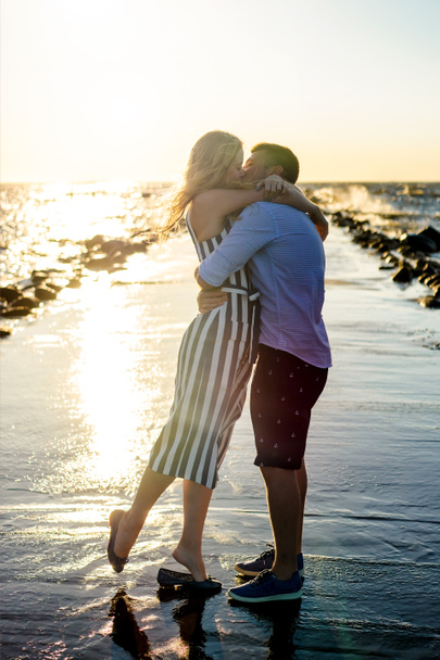 kaunis pari rakastunut halaus ja suudella meren rannalla auringonlaskun aikana Riiassa, Latvia
 - Valokuva, kuva