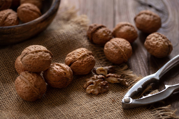 Walnuts kernels in wooden bowl on wooden background - Фото, изображение