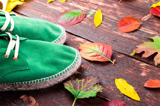 緑の男スエード ブーツ サンダル葉を持つ木製の背景。秋や冬の靴。フラットを置く.  - 写真・画像