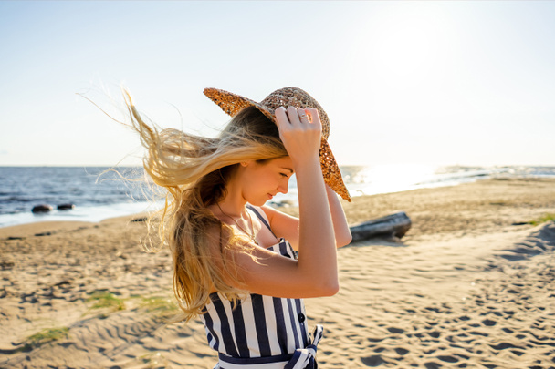 Widok z boku z atrakcyjna młoda kobieta w słomkowy kapelusz na piaszczystej plaży w Rydze, Łotwa - Zdjęcie, obraz