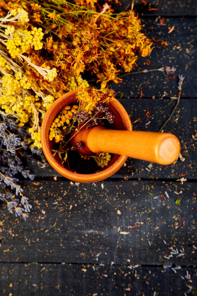 Healing herbs on wooden black table, herbal medicine. tutsan, sagebrush, oregano, helichrysum lavender - Fotó, kép