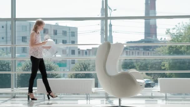 attractive businesswoman sitting on a white chair in a glass office and checks documents - Footage, Video