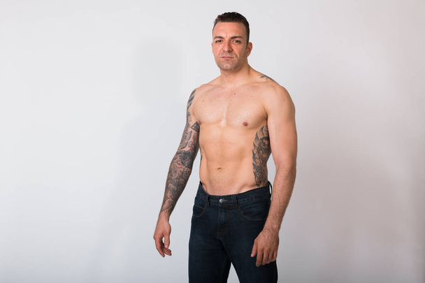 Retrato de hombre sin camisa con tatuajes contra fondo blanco
 - Foto, imagen