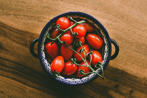 Closeup of healthy wet vibrant shiny red tomatoes as food photograhpy against wooden table background - Fotó, kép