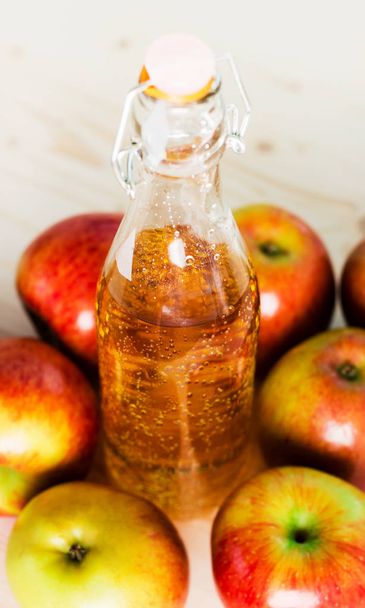 Bottle of fresh apple cider near autumn apples. Wooden background, space for text, view from above. - Photo, Image