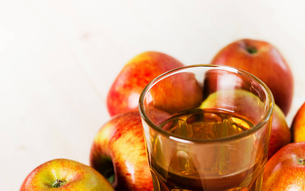 Glass of fresh apple cider near autumn apples. Wooden background, top view, space for text. - Photo, Image