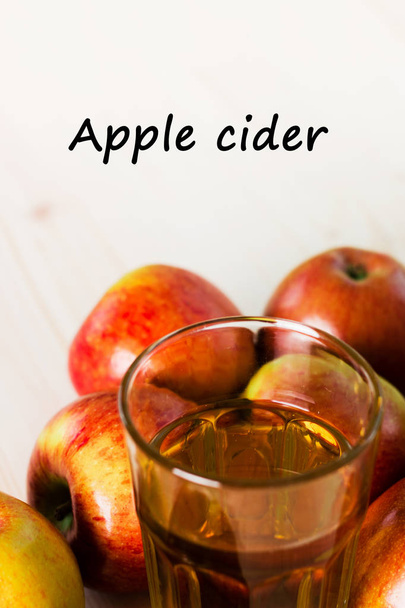 Glass of fresh apple cider  near autumn apples. Wooden background, text apple cider. Autumnal background. - Photo, Image