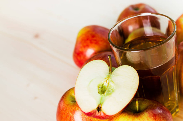 Ποτήρι φρέσκο μήλο μηλίτη και μισό μήλο κοντά φθινόπωρο μήλα. Ξύλινο υπόβαθρο, χώρο για το κείμενο. Φθινοπωρινό φόντο. - Φωτογραφία, εικόνα