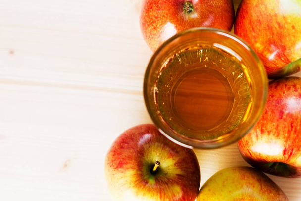 新鮮なリンゴ ジュースと秋のリンゴに近い半分リンゴのガラス。木製の背景、テキストのためのスペースの上から見る. - 写真・画像