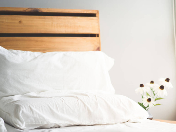 Minimal loft style wooden bed headboard with flowers in morning light. - Фото, изображение