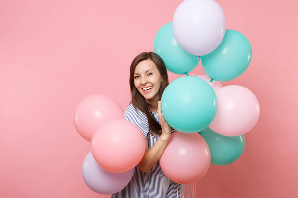 Portrait of beautiful smiling young happy woman wearing blue dress holding colorful air balloons isolated on bright trending pink background. Birthday holiday party, people sincere emotions concept - Photo, Image