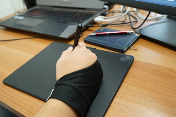 Edellä näkymä mies käsi suunnittelija freelancer käyttää grafiikka tabletti kosketusnäyttö ja kynä toimistossa
 - Valokuva, kuva