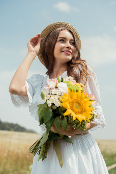 retrato de mujer sonriente en vestido blanco con ramo de flores silvestres en el campo
 - Foto, imagen