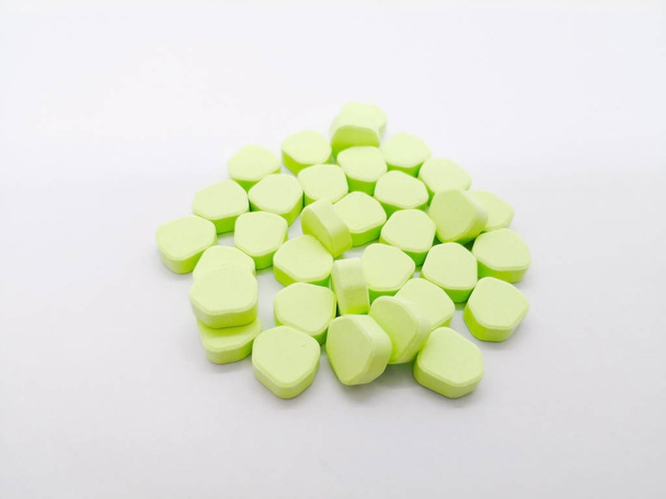 Medication and healthcare concept. Many green pentagon pills of  Paracetamol (Acetaminophen) 450 mg combined with Orphenadrine 35 mg . isolated on white background, used to treat injuries and other painful muscular conditions. Focus on foreground and - 写真・画像