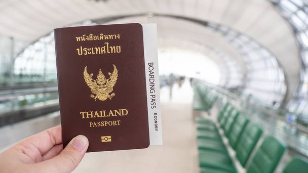 Nainen, jolla on Thaimaan passi ja tarkastuskortti kädessään lentokentällä istumaporttialueella
 - Valokuva, kuva
