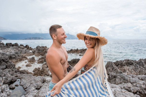 vista laterale di bella felice giovane coppia in piedi insieme sulla spiaggia rocciosa in montenegro
 - Foto, immagini